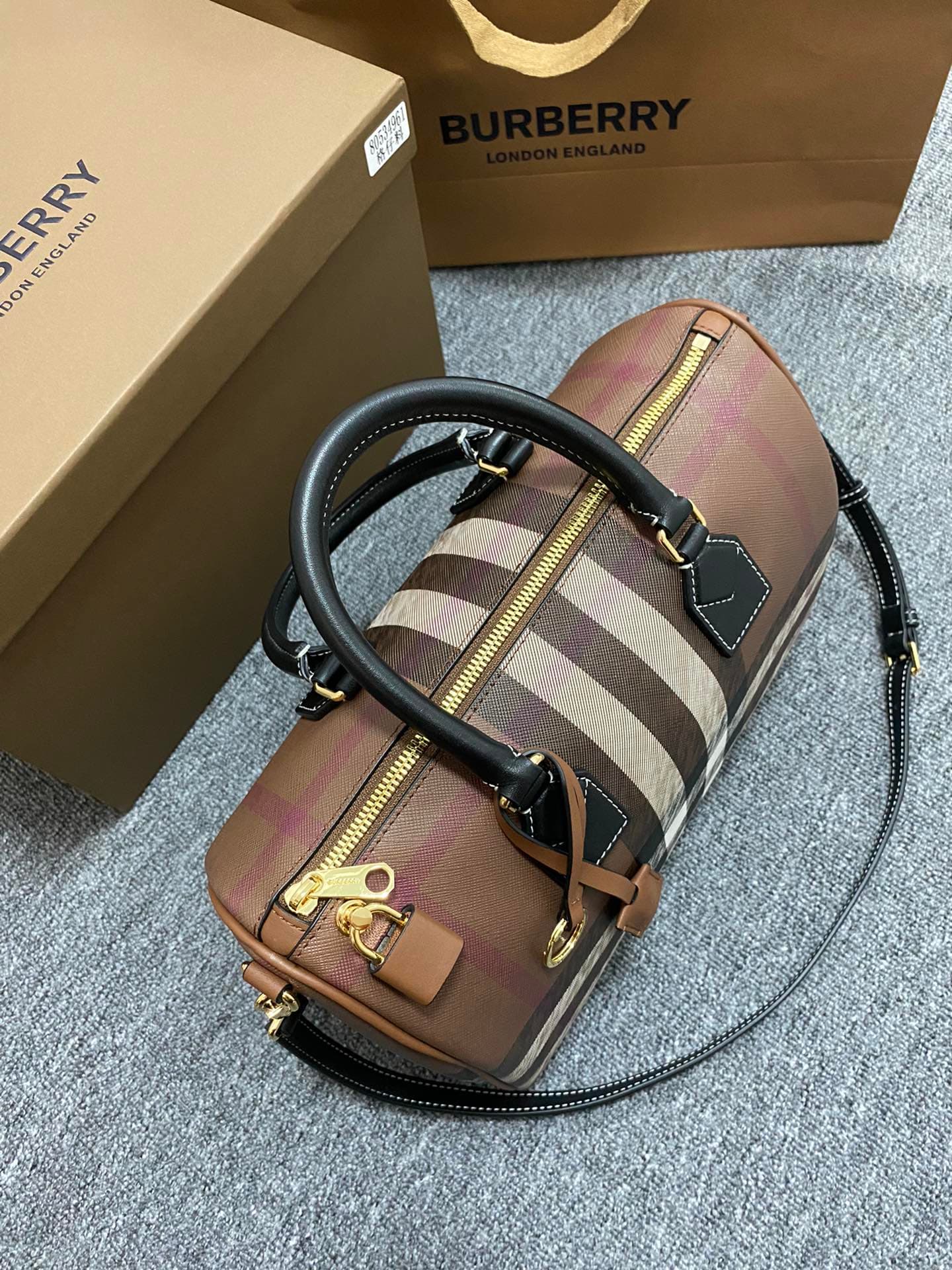 C68 The latest Italian-quality bowling bag from B brand is made of plaid material and leather with visible seams. It features a leather handle at the top, detachable and adjustable shoulder straps, zippers, as well as a leather-lined lock and luggage tag. — image 7