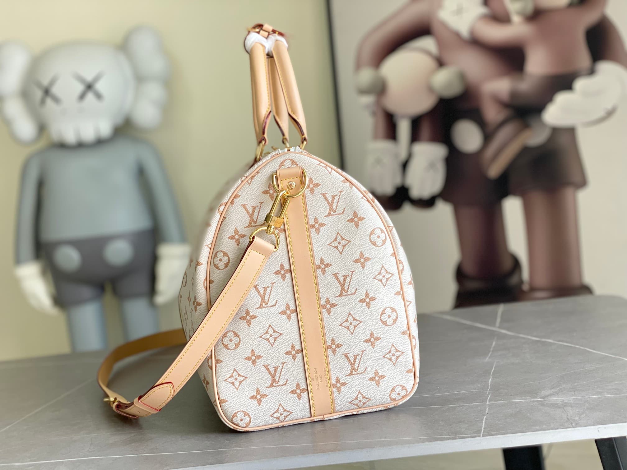 C5110 M29674 – White color; 163c01 – Dynamic design. This Keepall Bandoulière 45 travel bag is made from Monogram Dune-coated canvas, reflecting a casual style. Detailed craftsmanship is evident in the leather trim and the hand-sewn LV Crafty name tag. Th — image 2