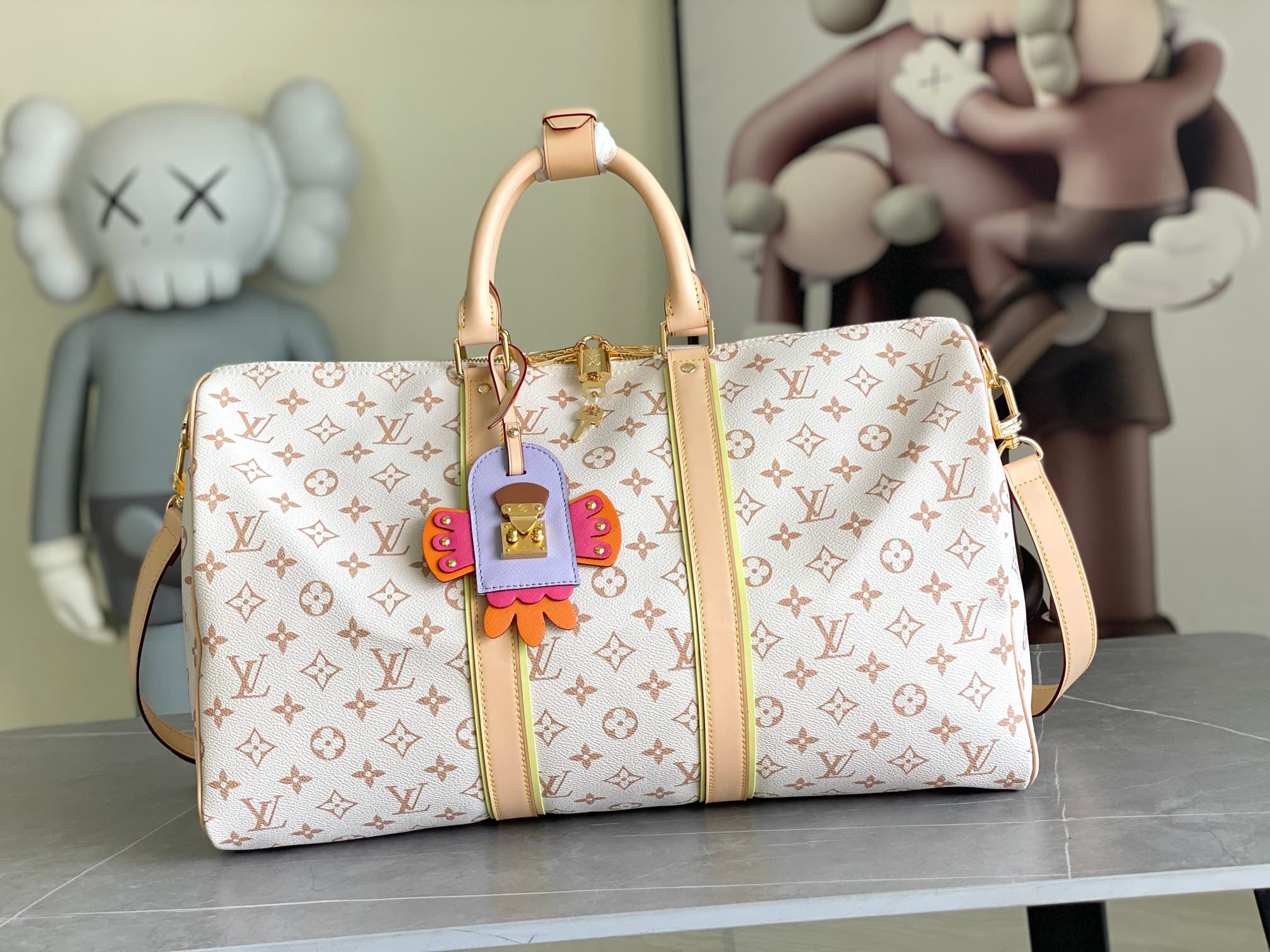 C5110 M29674 – White color; 163c01 – Dynamic design. This Keepall Bandoulière 45 travel bag is made from Monogram Dune-coated canvas, reflecting a casual style. Detailed craftsmanship is evident in the leather trim and the hand-sewn LV Crafty name tag. Th — image 1