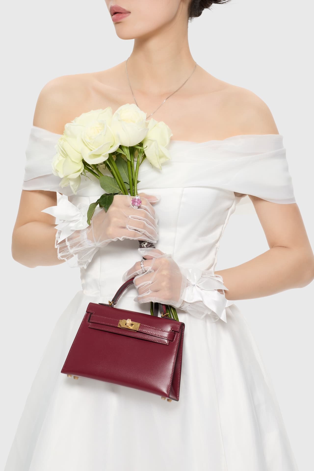 C4856 The white veil reflects purity; Kelly19 embodies Hermès’ red accents and perfection. The mini-sized design does not restrict the fluffy skirt edge; the intense red leather contrasts with the white satin. The H-button pairs well with the diamond deco — image 2