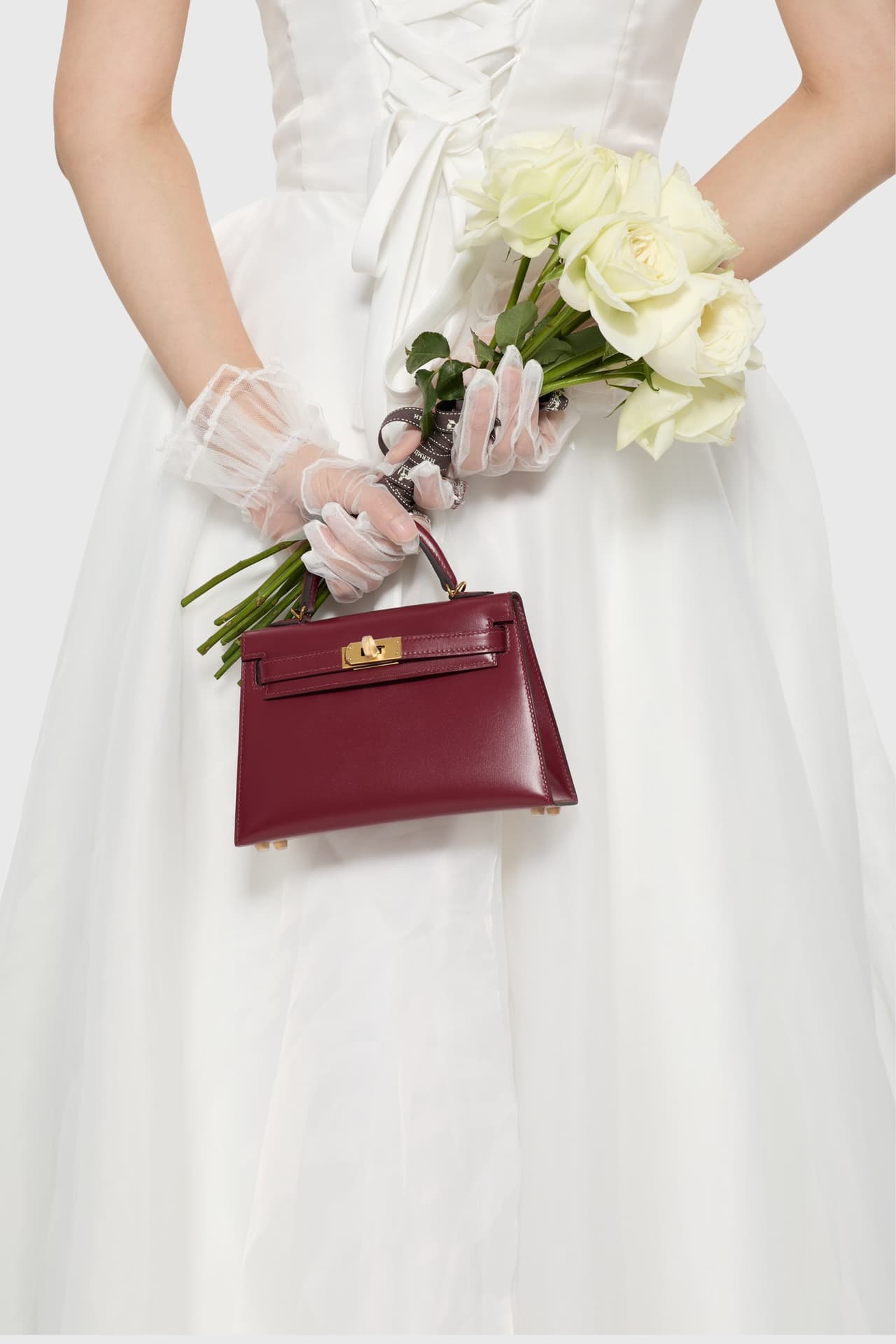 C4856 The white veil reflects purity; Kelly19 embodies Hermès’ red accents and perfection. The mini-sized design does not restrict the fluffy skirt edge; the intense red leather contrasts with the white satin. The H-button pairs well with the diamond deco — image 4