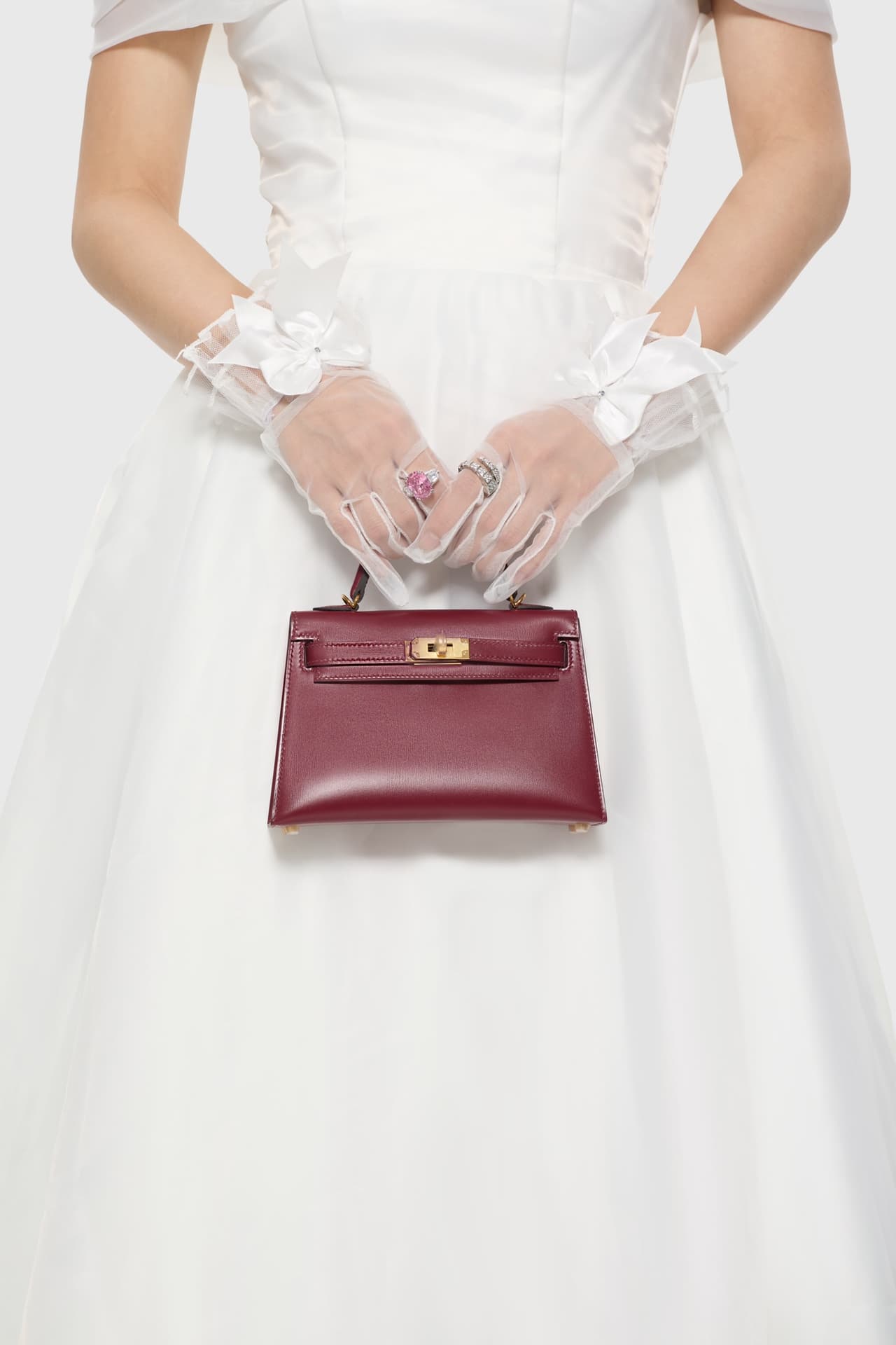 C4856 The white veil reflects purity; Kelly19 embodies Hermès’ red accents and perfection. The mini-sized design does not restrict the fluffy skirt edge; the intense red leather contrasts with the white satin. The H-button pairs well with the diamond deco — image 5