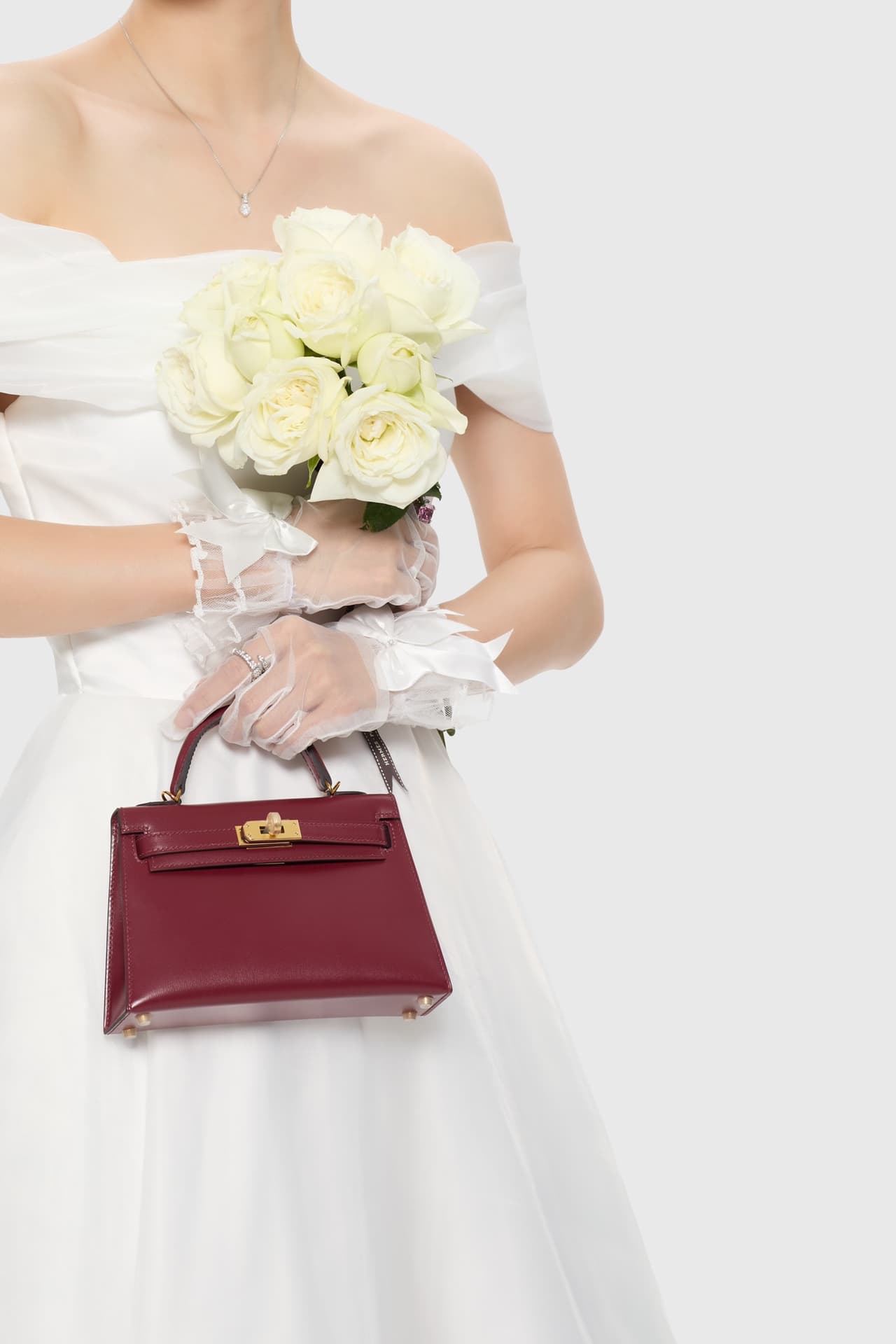C4856 The white veil reflects purity; Kelly19 embodies Hermès’ red accents and perfection. The mini-sized design does not restrict the fluffy skirt edge; the intense red leather contrasts with the white satin. The H-button pairs well with the diamond deco — image 3