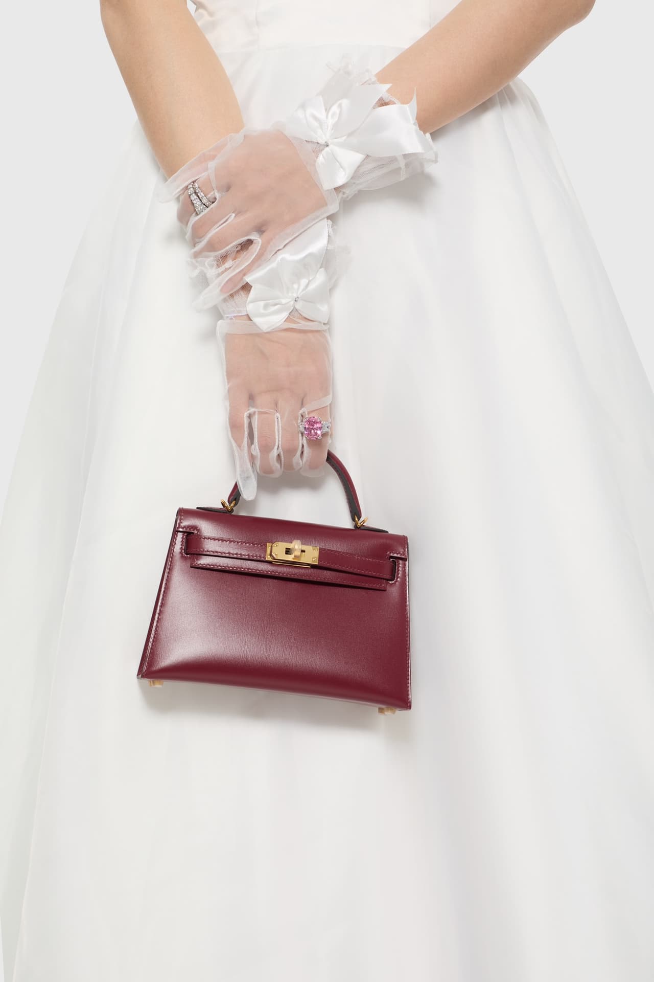 C4856 The white veil reflects purity; Kelly19 embodies Hermès’ red accents and perfection. The mini-sized design does not restrict the fluffy skirt edge; the intense red leather contrasts with the white satin. The H-button pairs well with the diamond deco — image 6