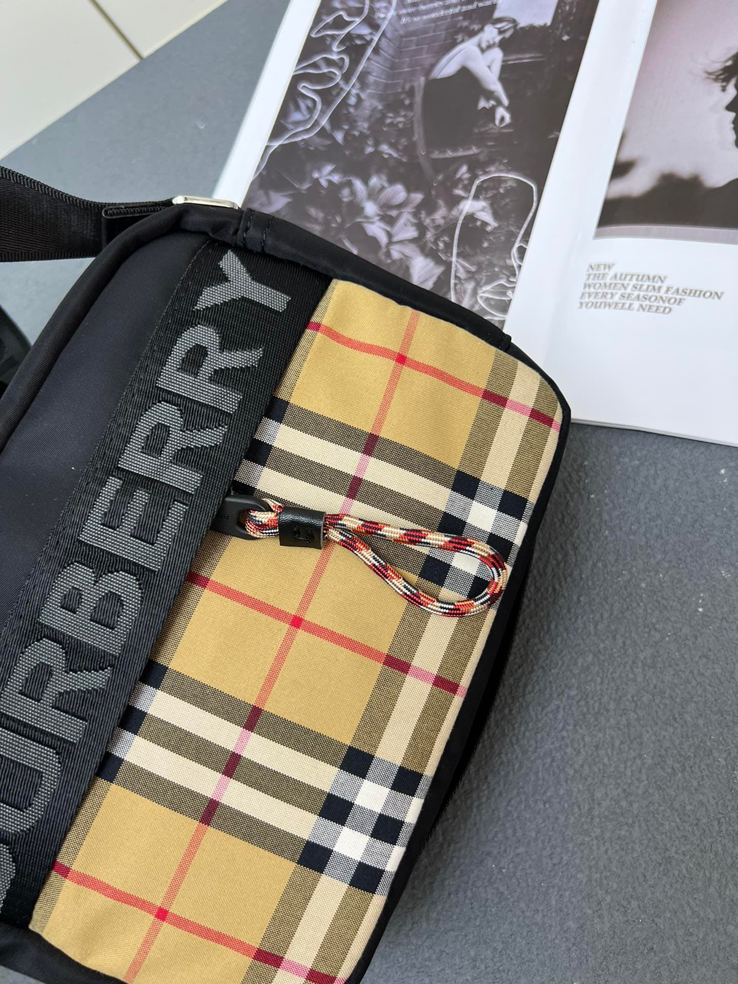 C36 [Brand B] 200: A vibrant decorative bag with a plaid pattern in the “Bur” style. It features a strap with a brand logo embroidered on it. There is an adjustable diagonal shoulder strap, as well as a zipper pocket. The 1 external pocket is opened using — image 5