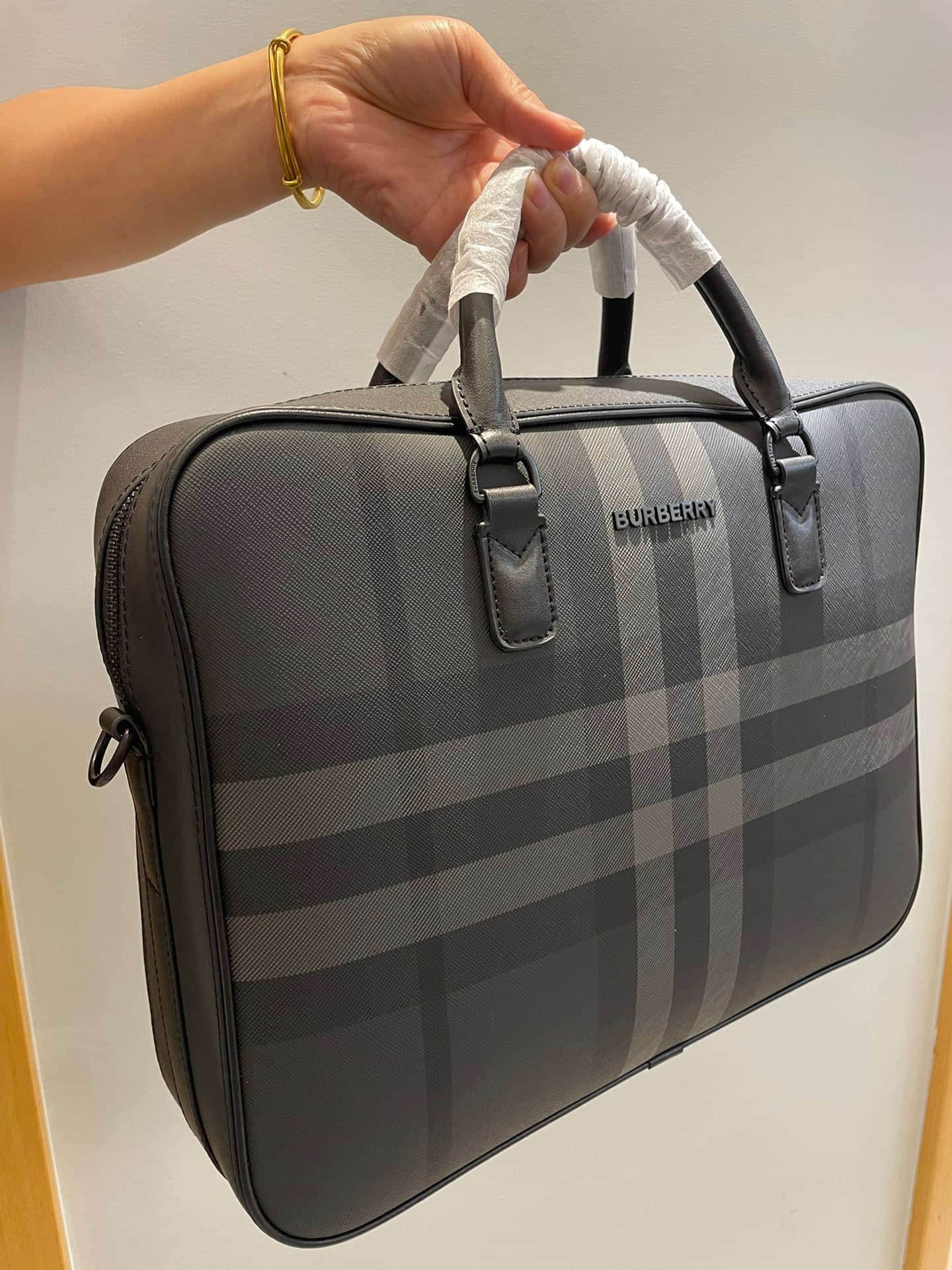 C8232 -B Brand’s latest briefcase is crafted from check pattern and Italian tanned leather, with a branded logo design. It can be carried in a handbag style, or it can be worn on the shoulder using detachable straps. At least 30% of the materials used in  — image 2