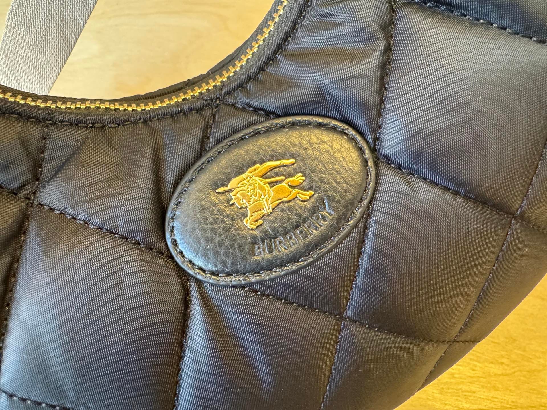 C44 [B’s top-tier original products] Slanted backpack, inspired by the elegance of English countryside. Made from quilted nylon blend fabric, adorned with fine-broken Bur pattern in the new season’s colors. Features leather trim and a knight’s seal in the — image 6