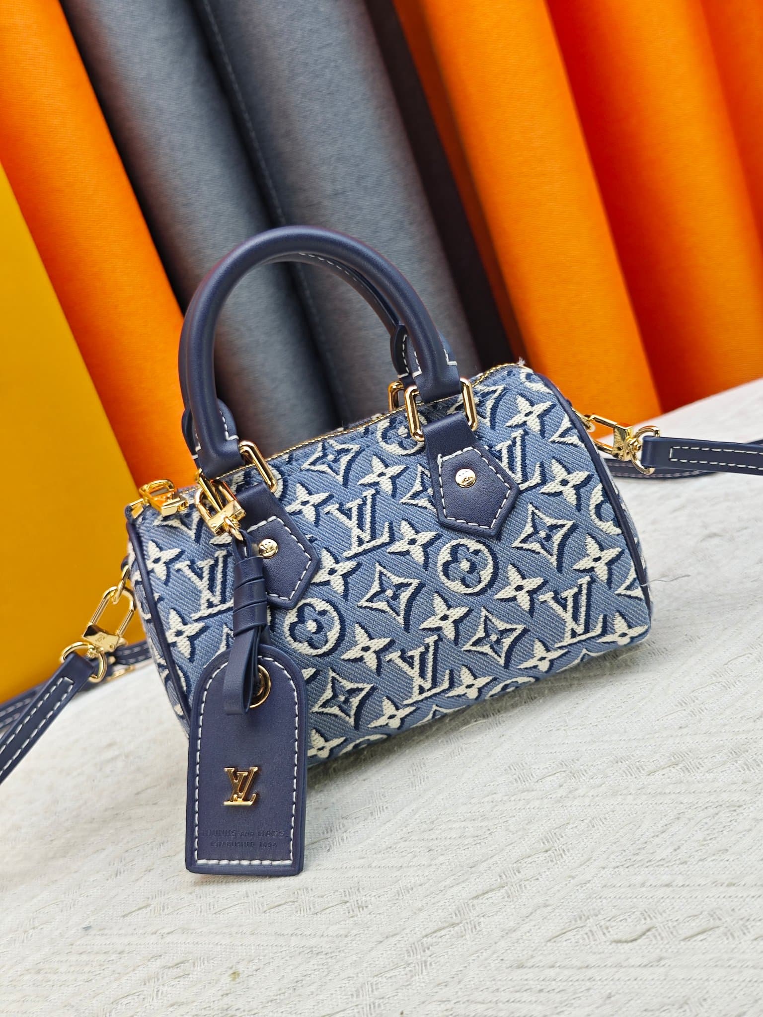 C5055 M28502 2A187 M81085 Batik. This Nano Speedy handbag features a delicate batik canvas design adorned with the Monogram Emblème logo. The bag’s body is styled in the traditional hard shell colors of the brand, and it comes with contrasting leather t — image 1
