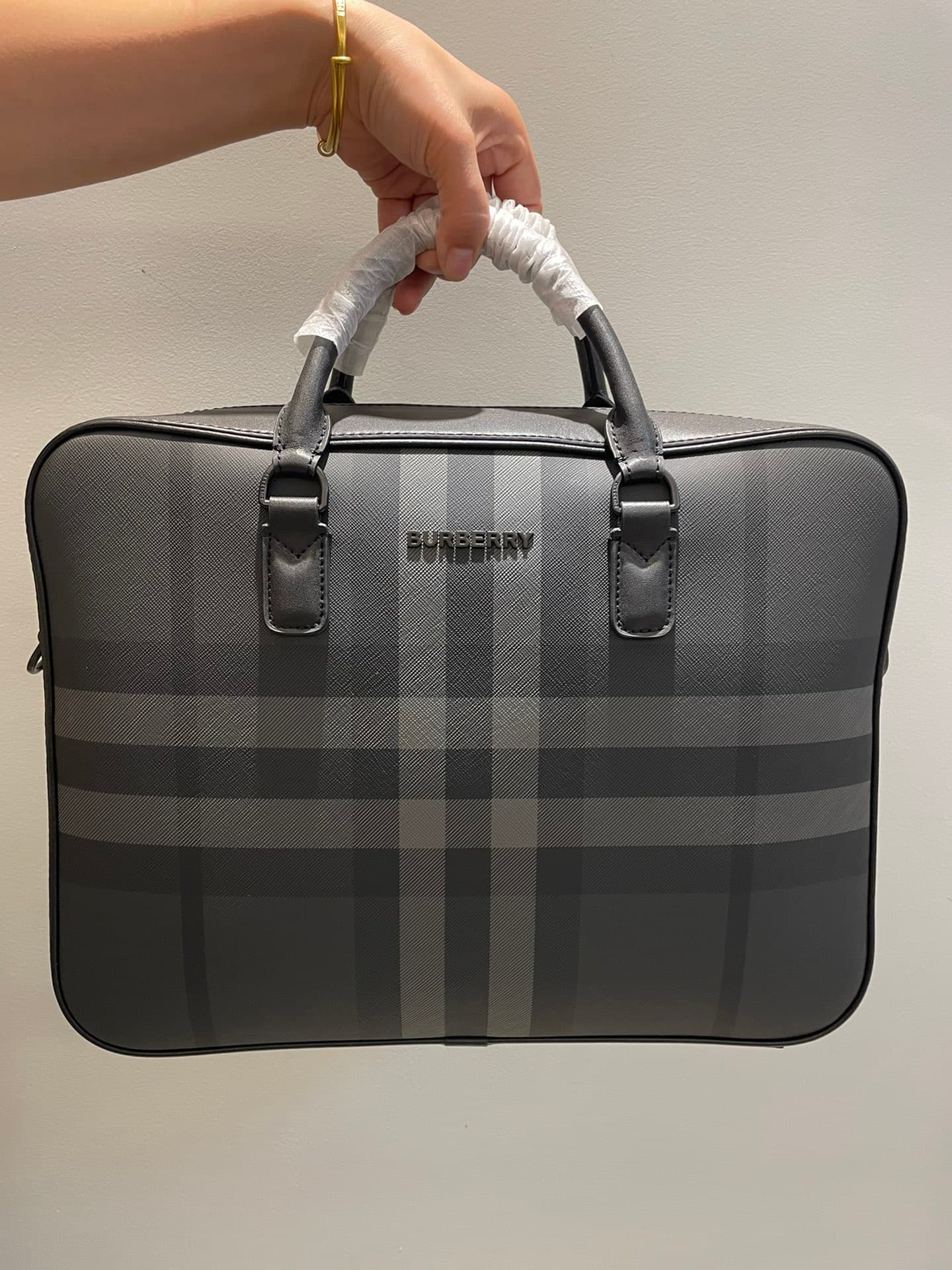 C8232 -B Brand’s latest briefcase is crafted from check pattern and Italian tanned leather, with a branded logo design. It can be carried in a handbag style, or it can be worn on the shoulder using detachable straps. At least 30% of the materials used in — image 1