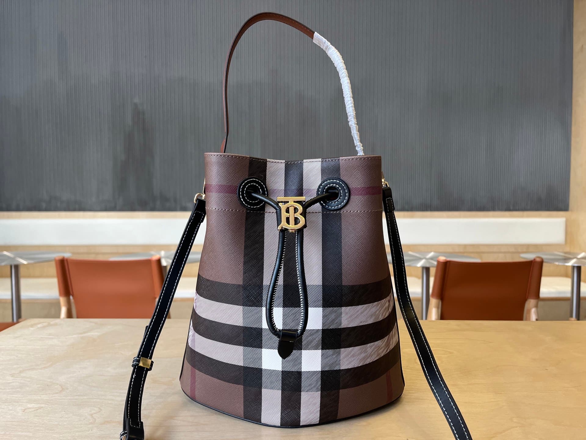 C13 B brand's latest bucket bag, crafted from large-scale check and ribbed leather material, adorned with the TB exclusive logo. This bag is a new member of the TB bag collection, featuring a detachable adjustable diagonal shoulder strap and an inner pock — image 1