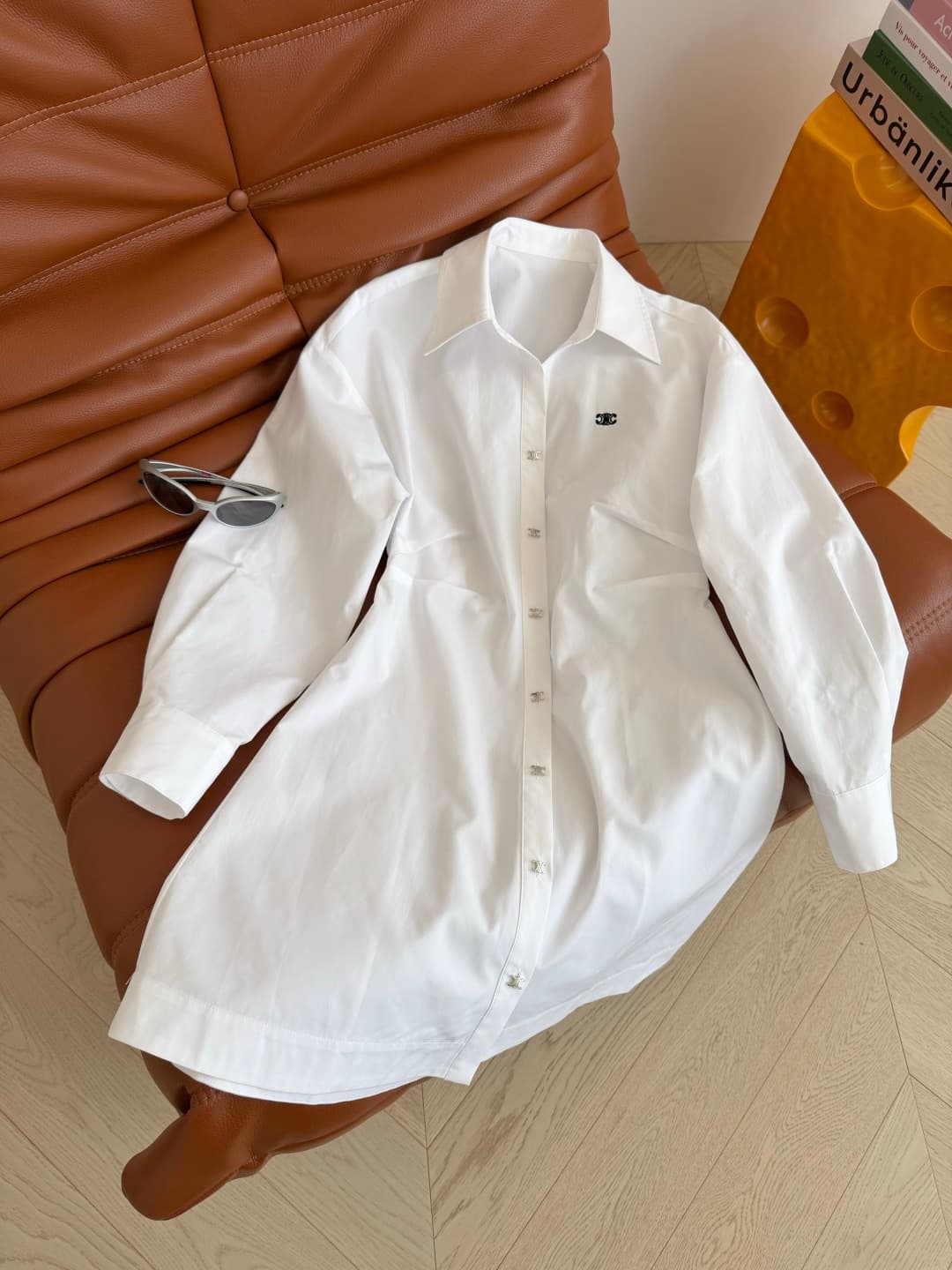 C18428 26 Spring/Summer – Triumph Arch logo embroidered design dress. A row of silver Triumph Arch buttons for decoration. An essential shirt dress for daily use; suitable for both work and vacation shopping. Shoulder-pull design, with a pleated waistline — image 1